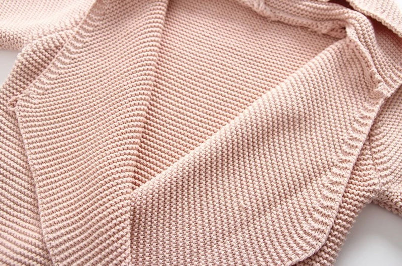 Close up of the knitted baby wrap in light pink.