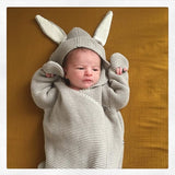 Baby in gray knitted baby wrap with bunny ears hood.