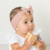 Baby wearing soft fit headband with bow in light pink.