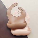 Reusable silicone bibs in tan and pink.