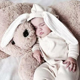 Baby sleeping in white long sleeve jumpsuit with bunny ears hood.