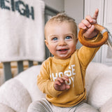 Baby playing with handmade rainbow macrame wooden teether in gray.