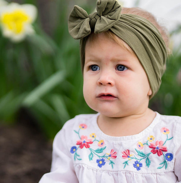 Baby wearing soft fit headband with bow in olive green.