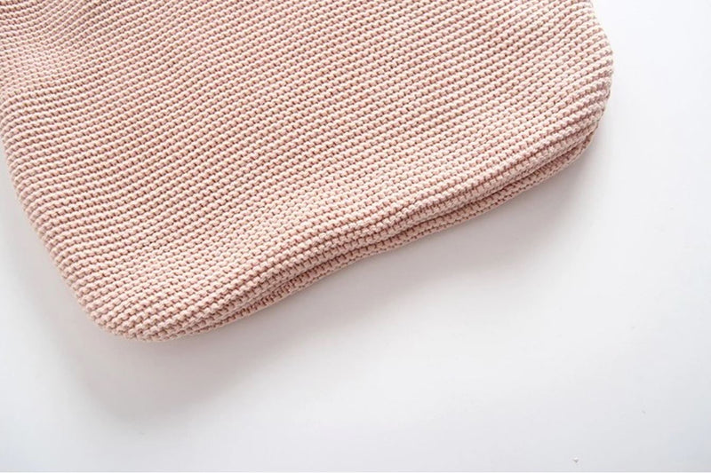 Close up of the bottom of the knitted baby wrap in light pink.