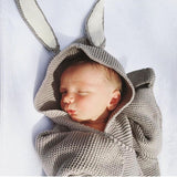 Baby in gray knitted baby wrap with bunny ears hood.