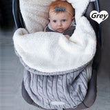 Baby in stroller laying on top of knit swaddle wrap in gray.  The swaddle is lined and for winter use. 