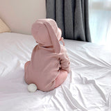 Baby in bed wearing 3 piece matching set in rose.  Set includes bunny ears hat, long sleeve onesie and knee high socks.