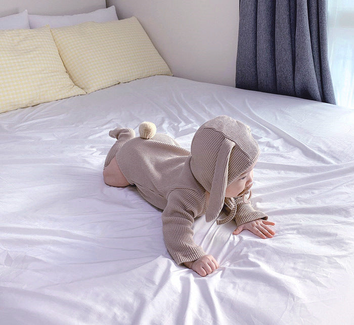 Baby in bed lying down wearing 3 piece matching set in mauve.  Set includes bunny ears hat, long sleeve onesie and knee high socks.