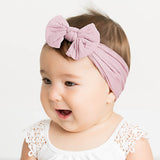 Baby wearing soft fit headband with bow in light pink.
