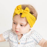 Baby wearing soft fit headband with bow in yellow.