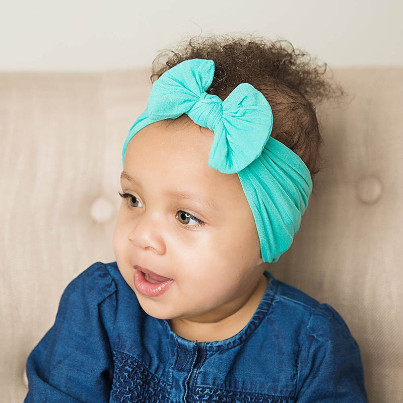 Baby wearing soft fit headband with bow in turquoise.