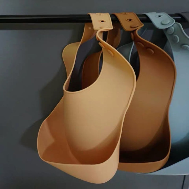 Reusable silicone bibs in tan, brown and blue.