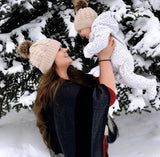 Mommy and baby wearing matching knitted pom pom hats in tan.