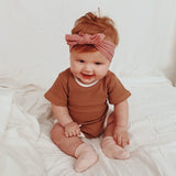 Baby wearing tee shirt and shorts set in brown with white trim.