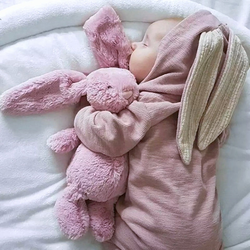 Baby sleeping in pink long sleeve jumpsuit with bunny ears hood.