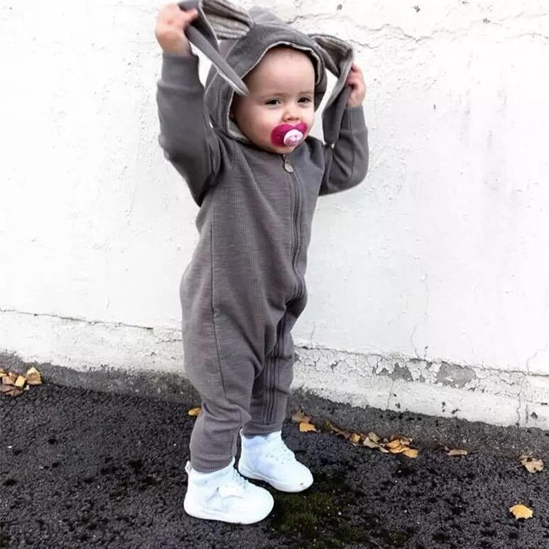 Baby wearing a grey long sleeve jumpsuit in grey with bunny ears hood.