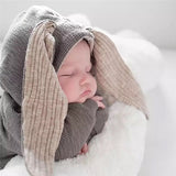 Baby sleeping in grey long sleeve jumpsuit with bunny ears hood.
