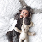 Baby in grey long sleeve jumpsuit with bunny ears hood.